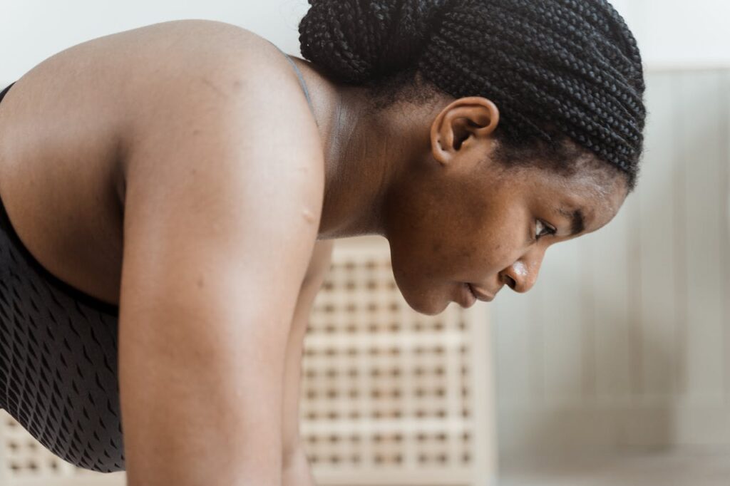Woman showing signs of neck and shoulder tension during physical movement indoors